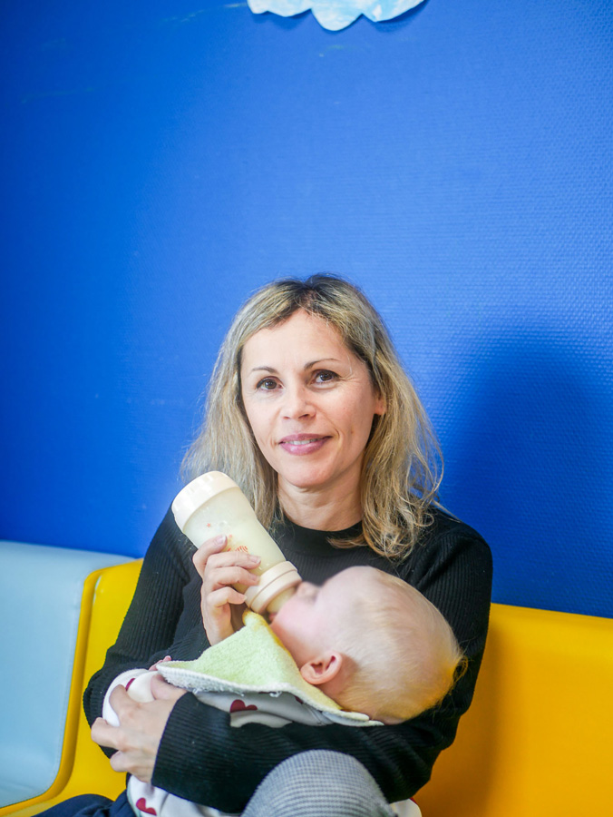 femme souriante en train de donner le biberon à un bébé - Équipe pédagogique de la crèche multilingue